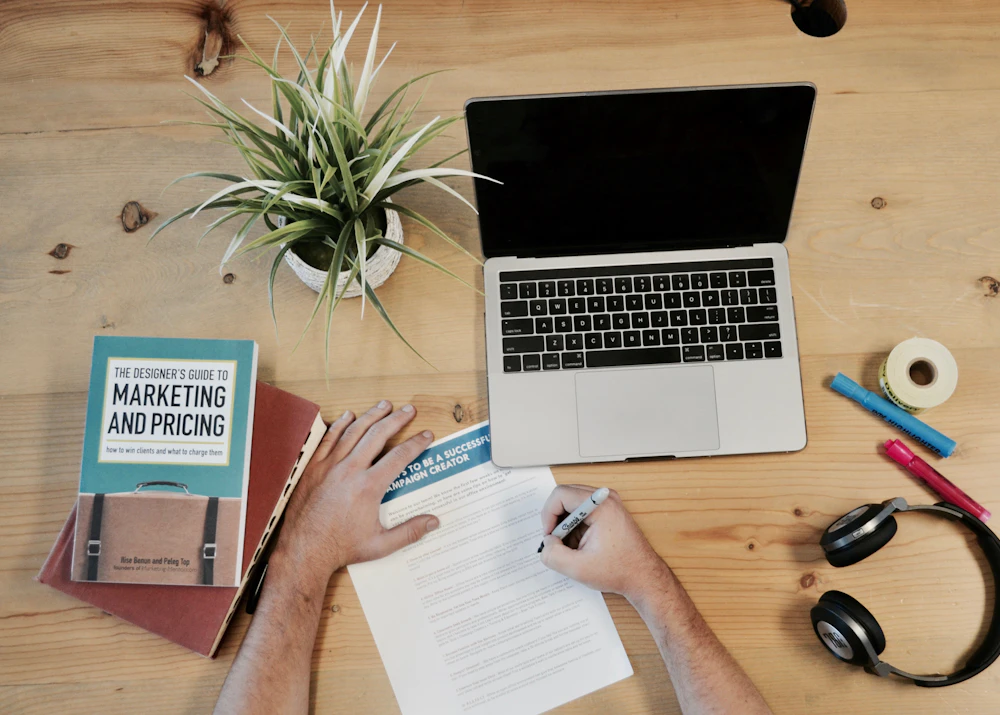 Content strategy planning at a desk with notes, laptop and marketing book