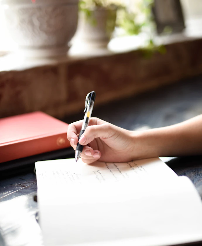 Person writing on paper with a pen