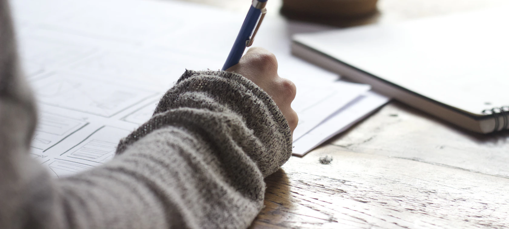 Copywriter writing notes by hand at a wooden table