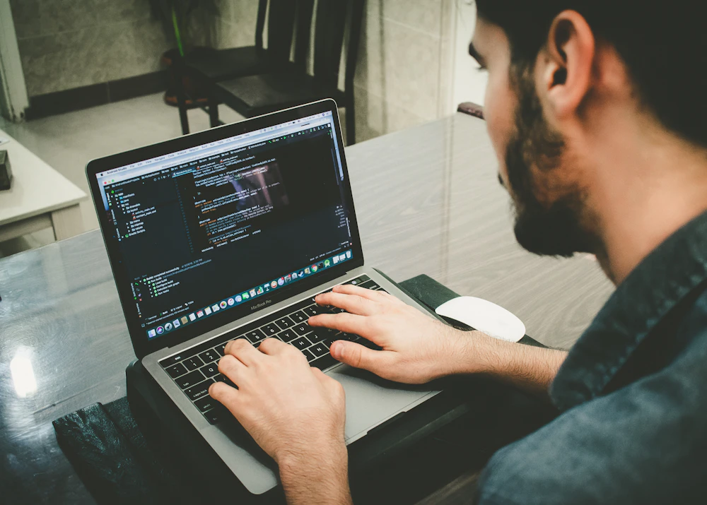 Mobile app developer writing code on a laptop