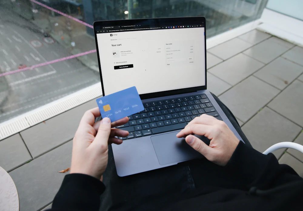 Shopper holding a credit card at a laptop