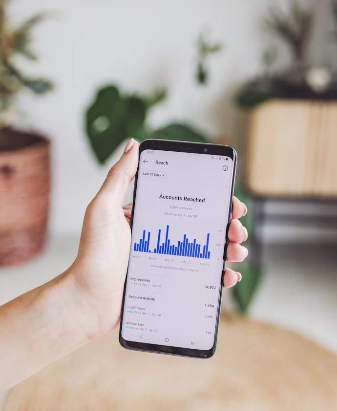 Hand holding a smartphone with an advertising results chart