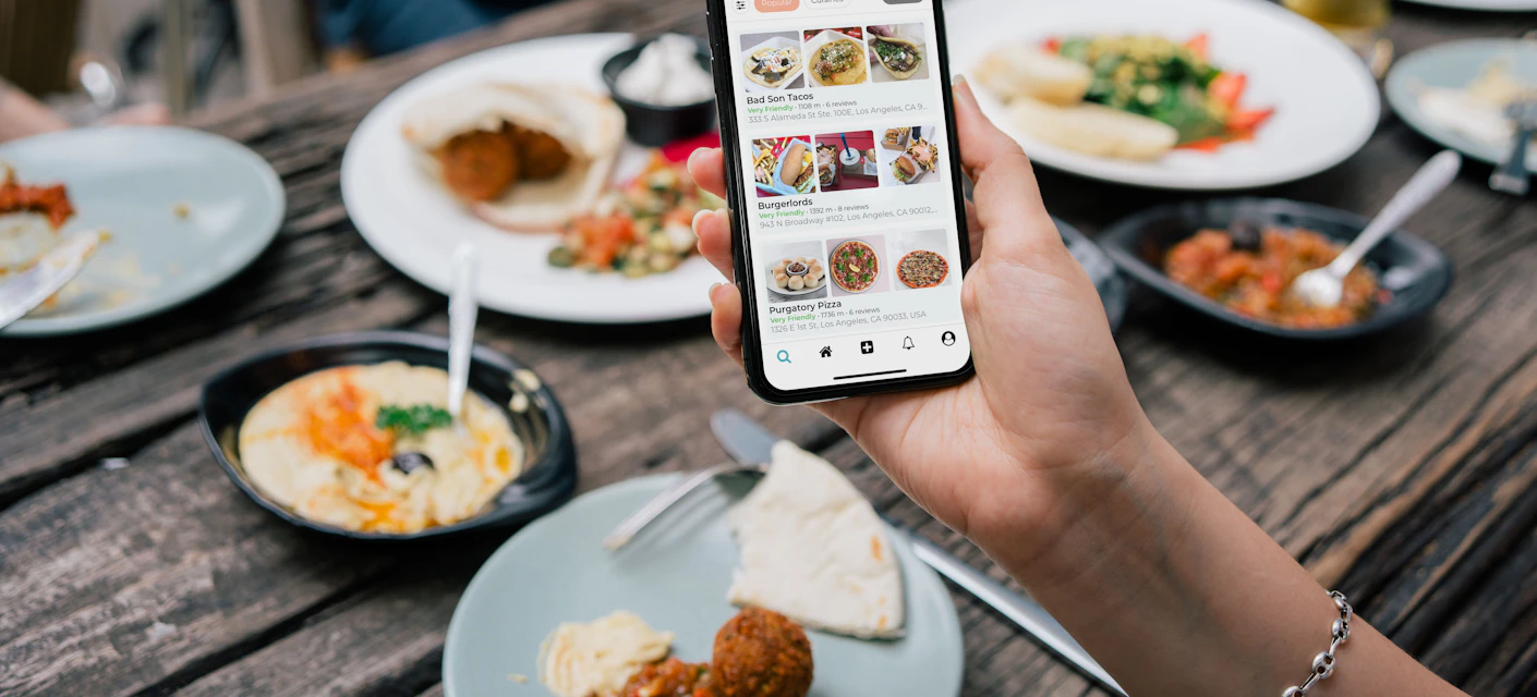 Phone showing a food feed above a table of dishes