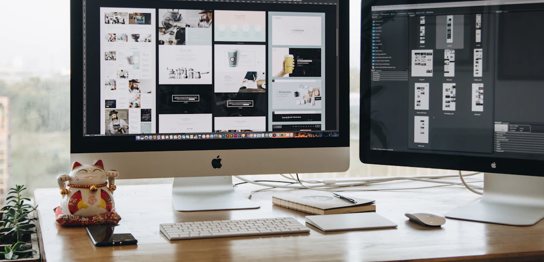 Two monitors showing website designs on a desk