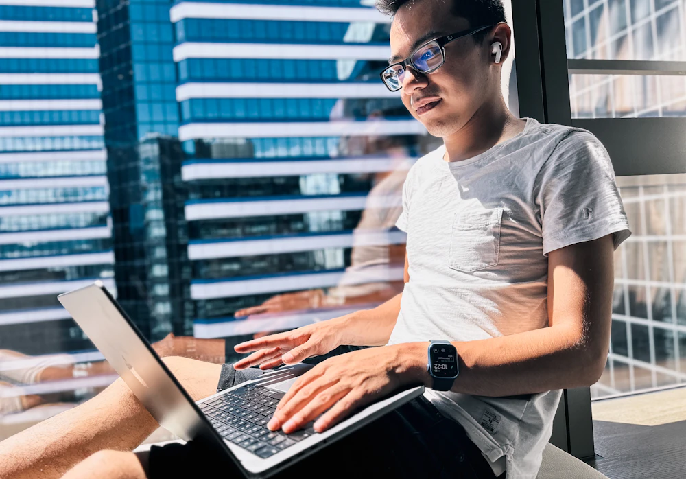 Man working on a laptop by a window